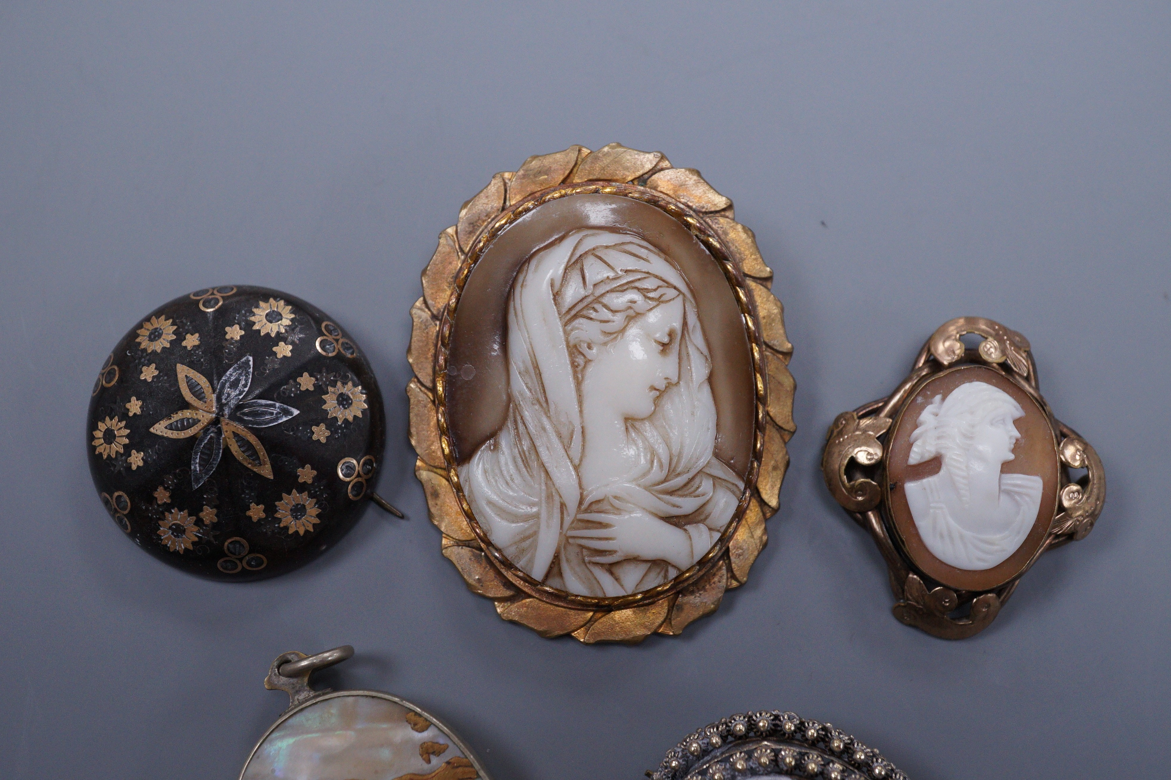 A Victorian gold pique circular brooch, 3cm (a.f.), two cameo brooches, a gilt metal brooch and a Japanese mother of pearl locket